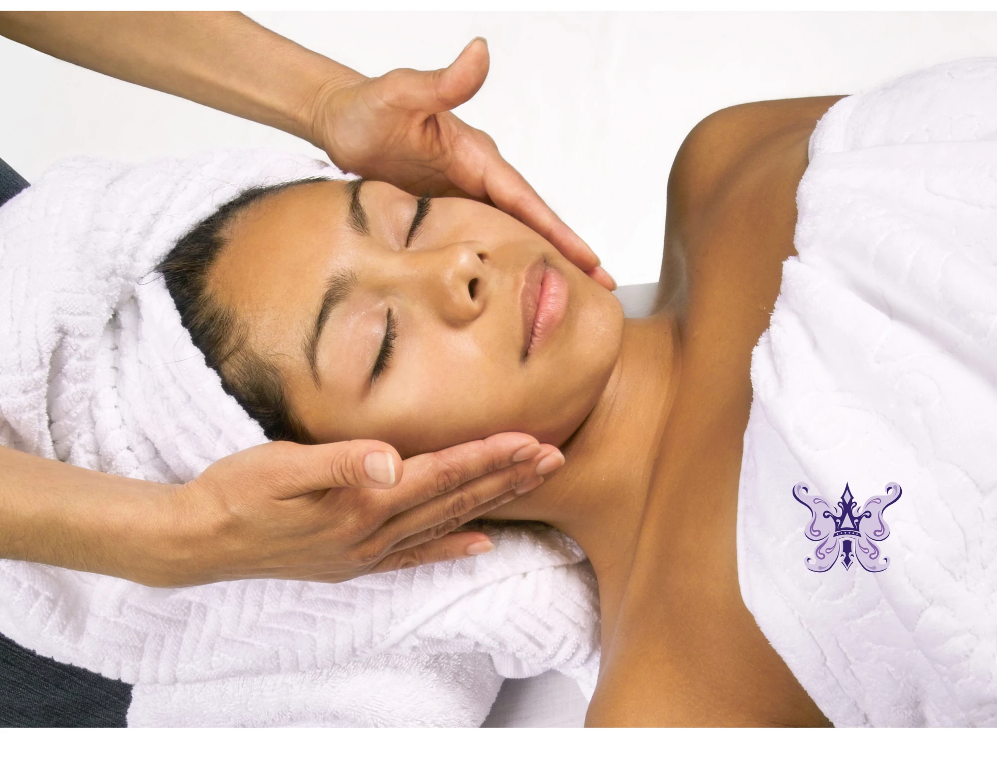 A client relaxing during a customized facial at Anastasia’s Crown while an esthetician gently examines her skin.