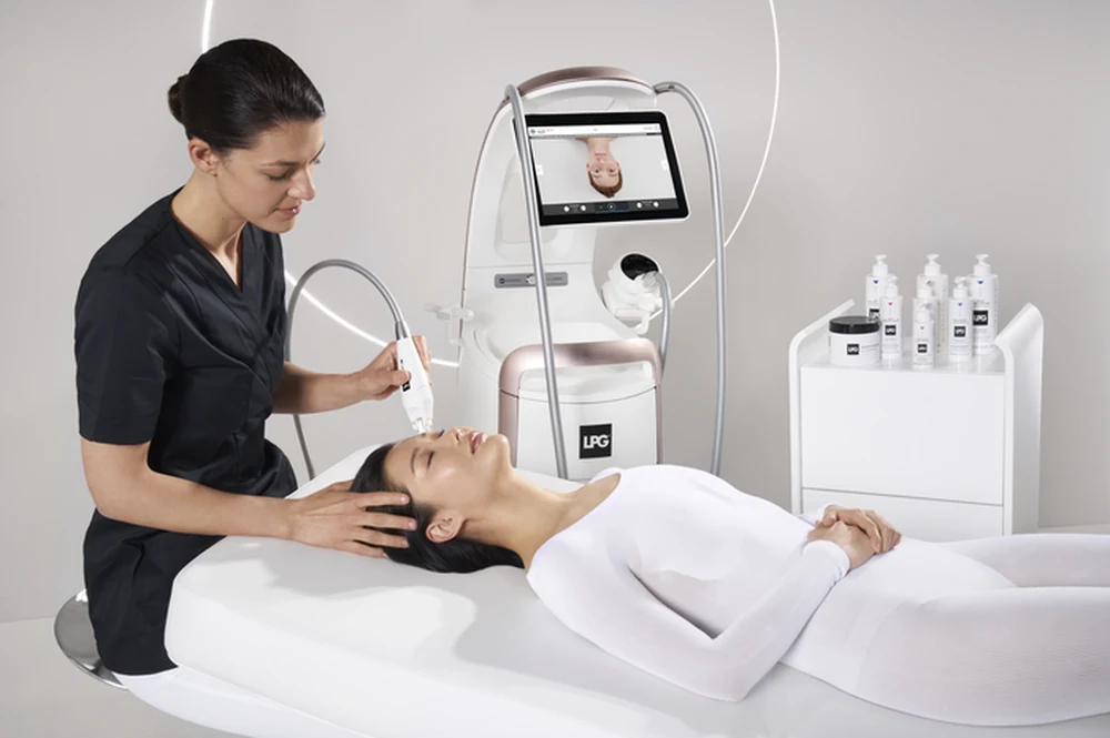 A Face Endermologie treatment using the LPG facial treatment handpiece while the client relaxes beside the LPG machine.